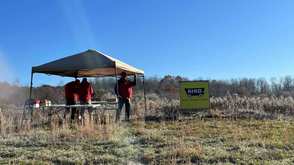 KIKO Auctioneers in a field prepare for land auction, with tent and auction block.
