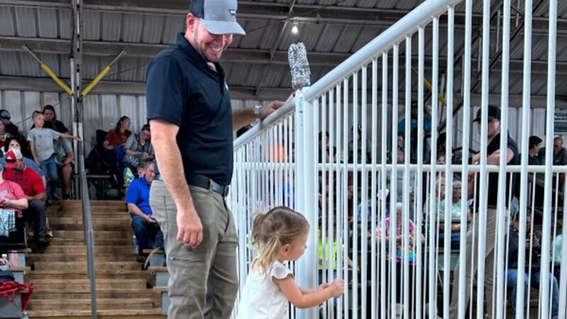 KIKO realtor and auctioneer, Ryan Yoder, smiles as he looks down at his daughter during the Tuscarawas County Fair.